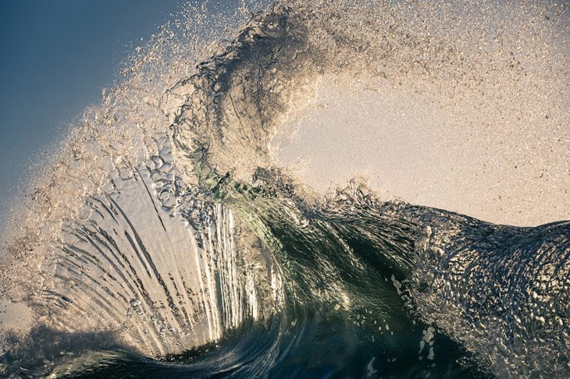 透明海浪在逆光中卷起并散成水滴